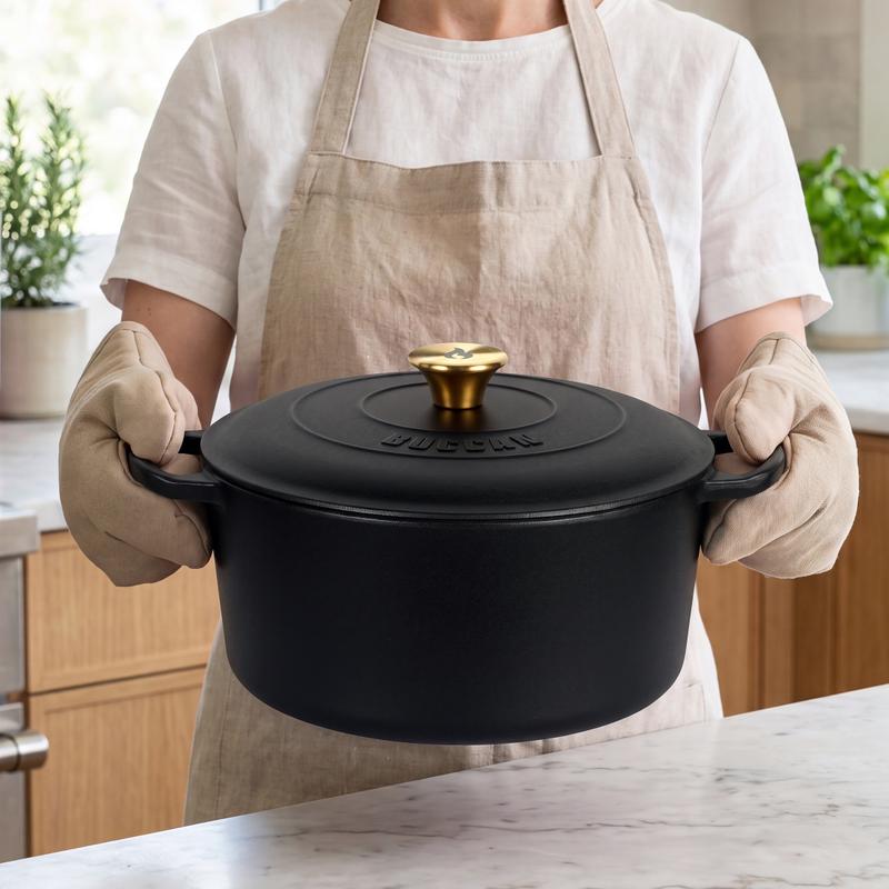 Vrouw met ovenwanten houdt de zwarte gietijzeren braadpan van Action vast Vrouw met ovenwanten houdt de zwarte gietijzeren braadpan van Action vast
