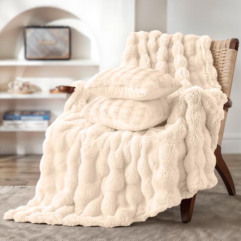 Crème-witte Pom Pom Fur plaid van Action met twee sierkussens over een houten stoel Crème-witte Pom Pom Fur plaid van Action met twee sierkussens over een houten stoel