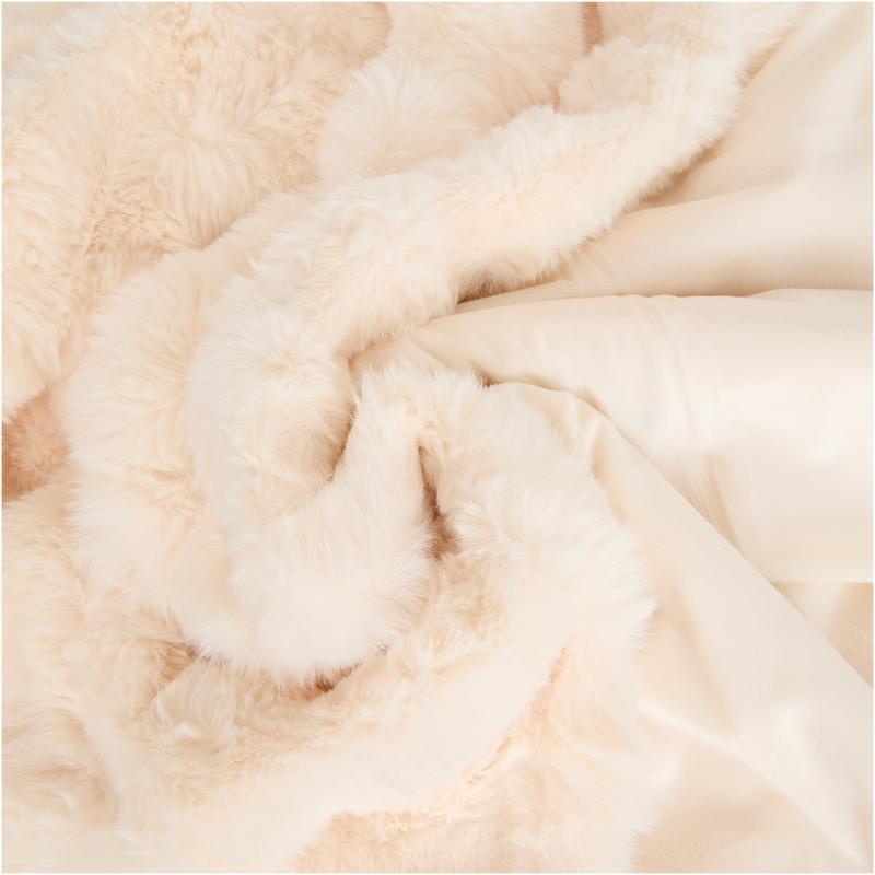 Close-up van de pluizige crème-witte stof van de Pom Pom Fur plaid van Action Close-up van de pluizige crème-witte stof van de Pom Pom Fur plaid van Action