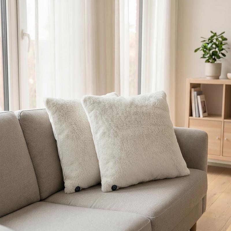 Twee lichtgrijze warmtekussens van Action op een beige bank in een lichte woonkamer